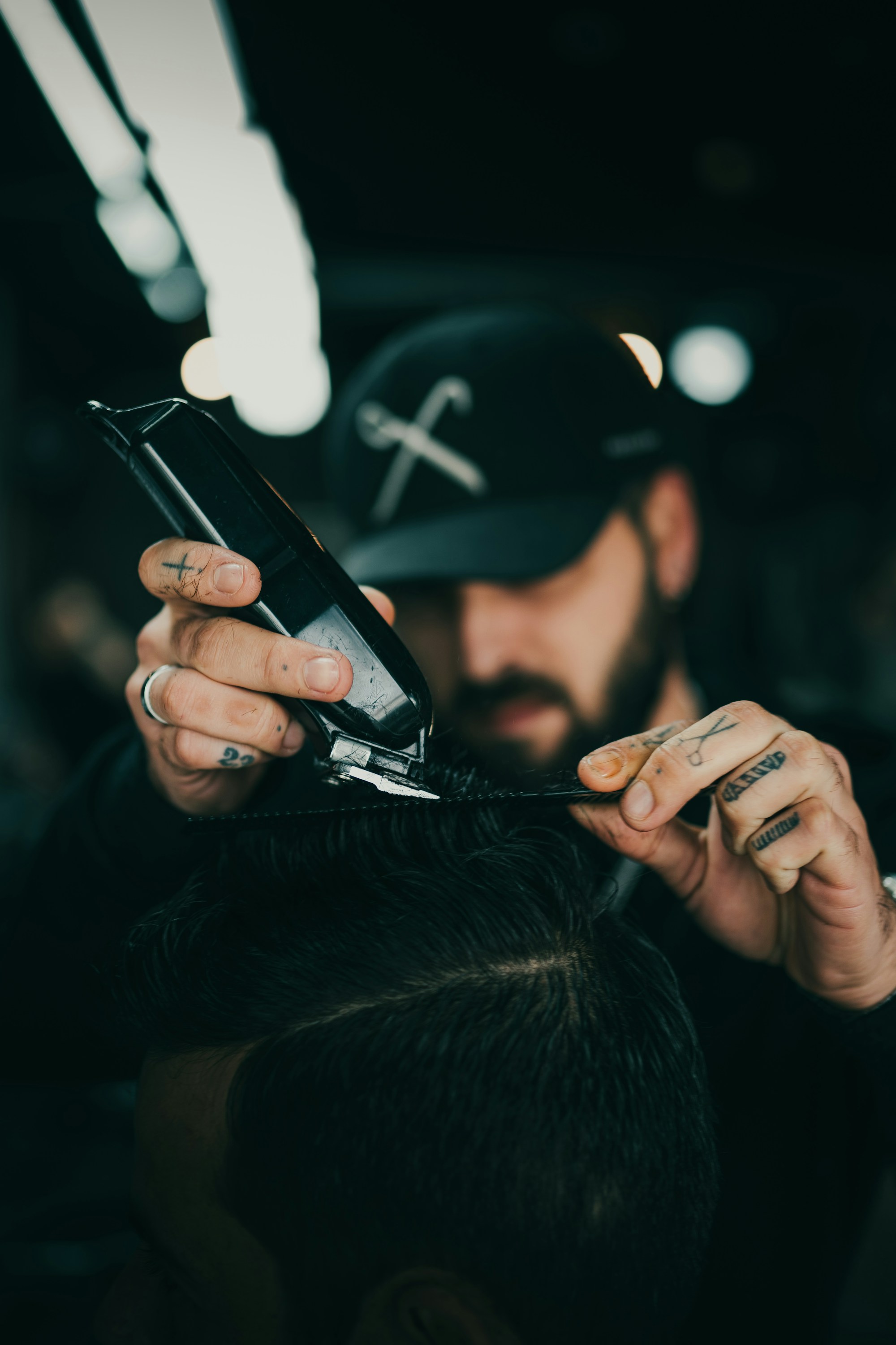 A barber carefully shaping a haircut with clippers and a comb